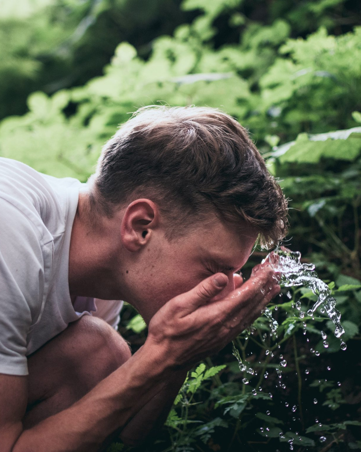Man washing his face with fresh water outside