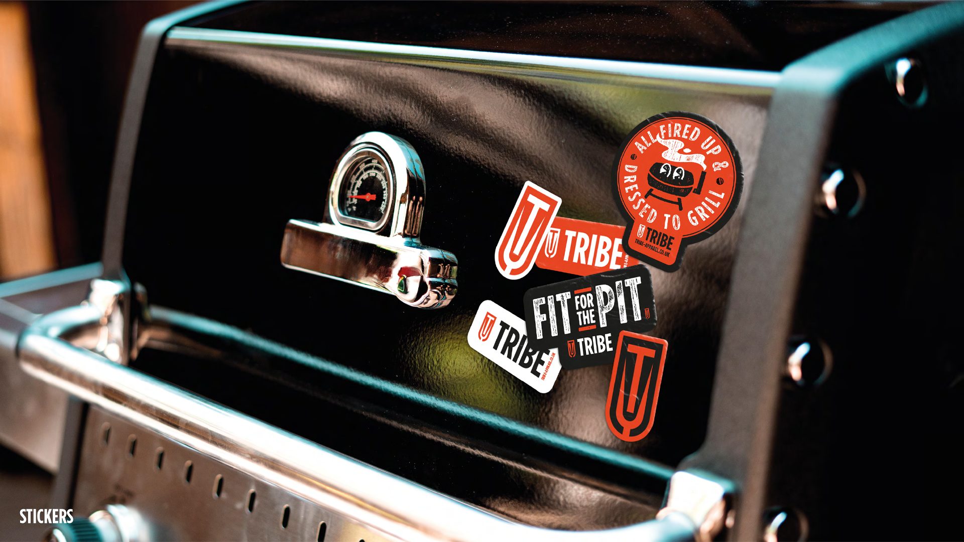 Close-up of Tribe branded stickers on the surface of a shut BBQ grill.