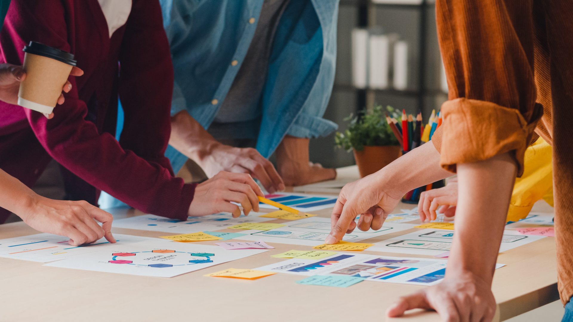 People gathered around a table reviewing post-it notes and printed materials.