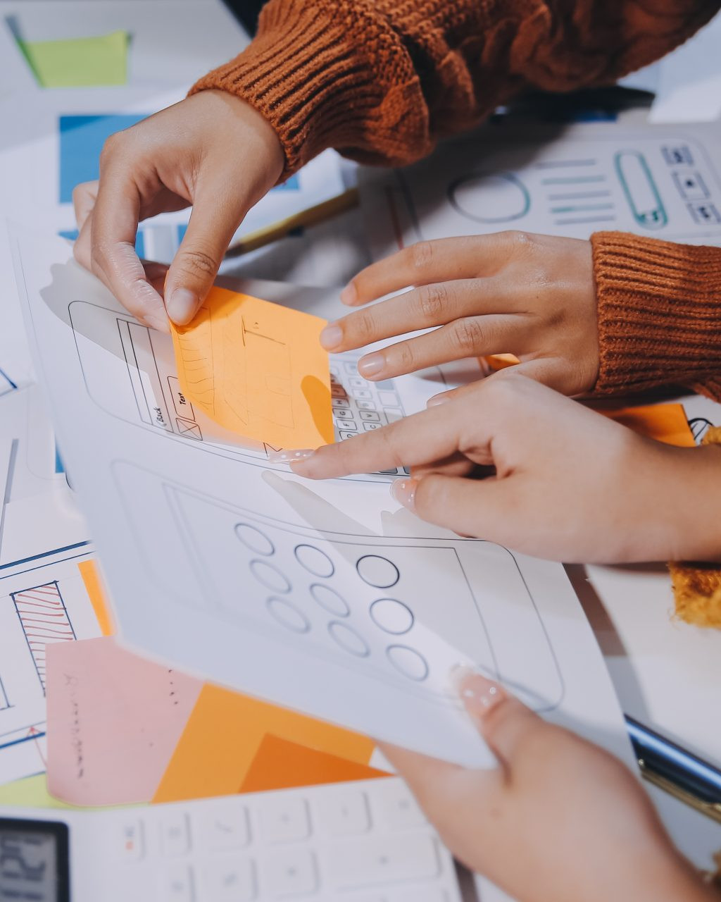 People gathered around a table reviewing UX documents, notes, and planning materials.