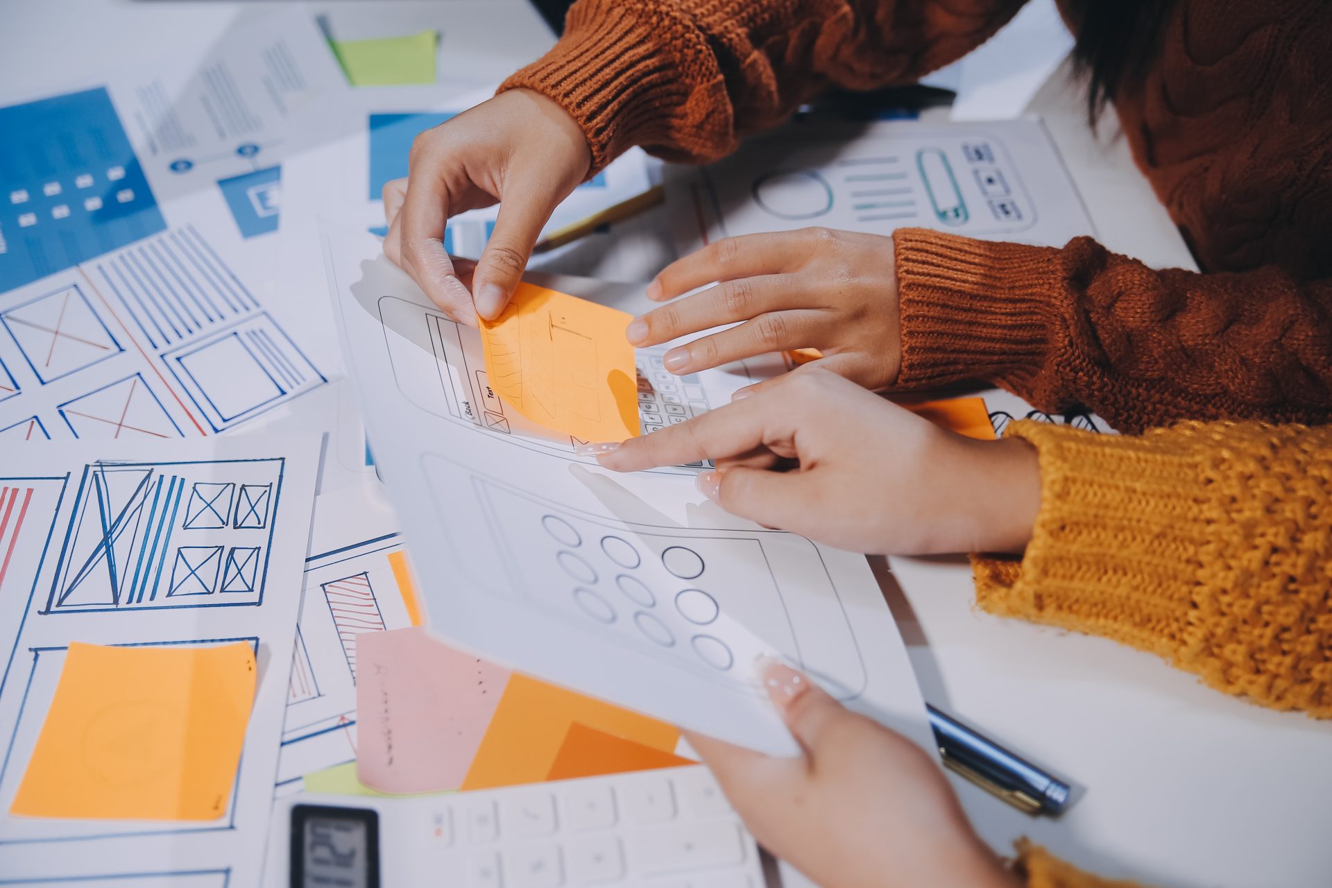 People gathered around a table reviewing UX documents, notes, and planning materials.