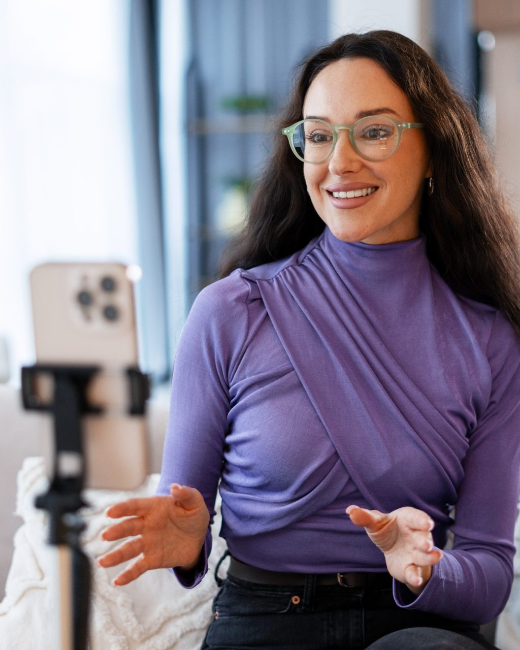 Woman looking into a smartphone camera mounted on a tripod.
