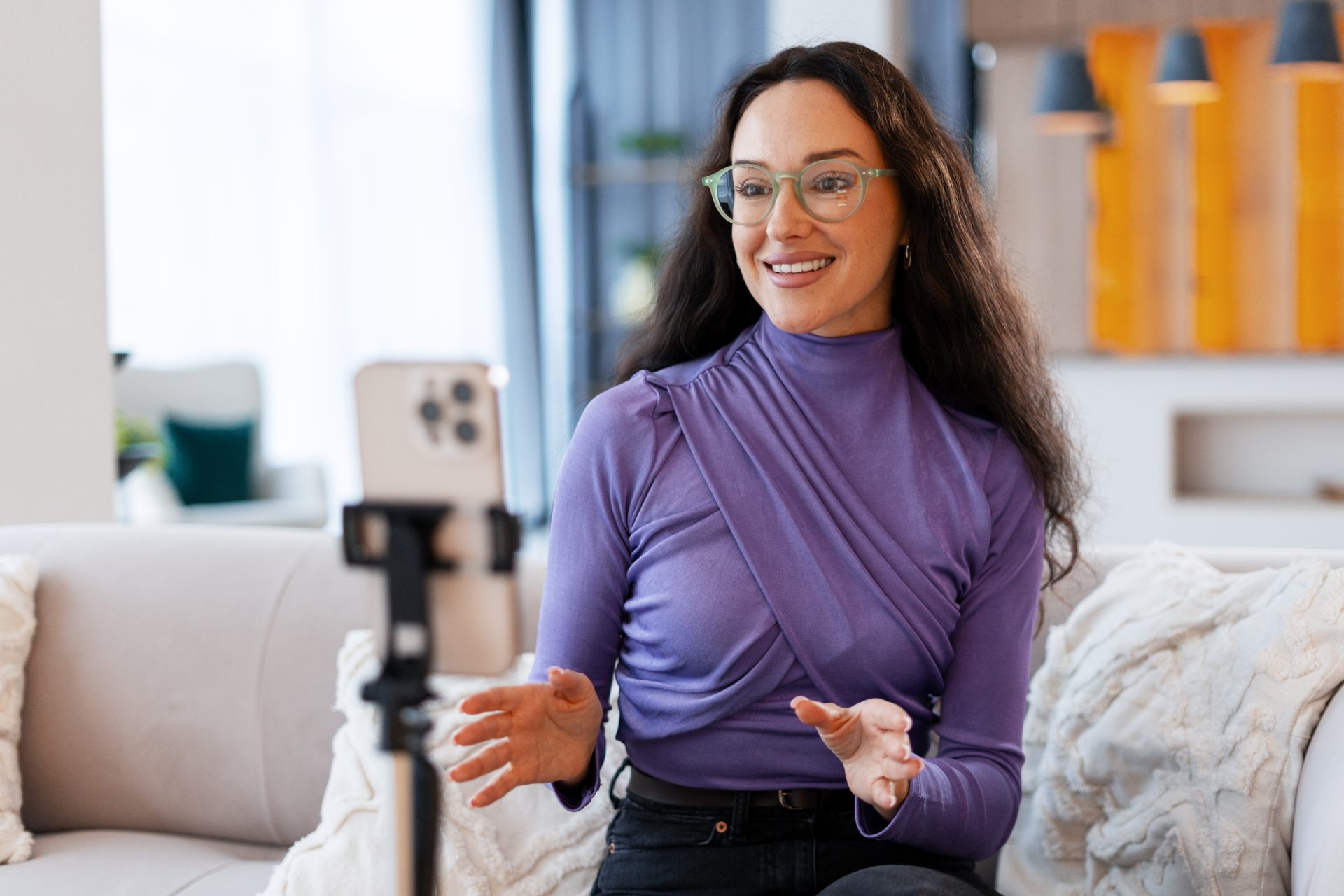 Woman looking into a smartphone camera mounted on a tripod.