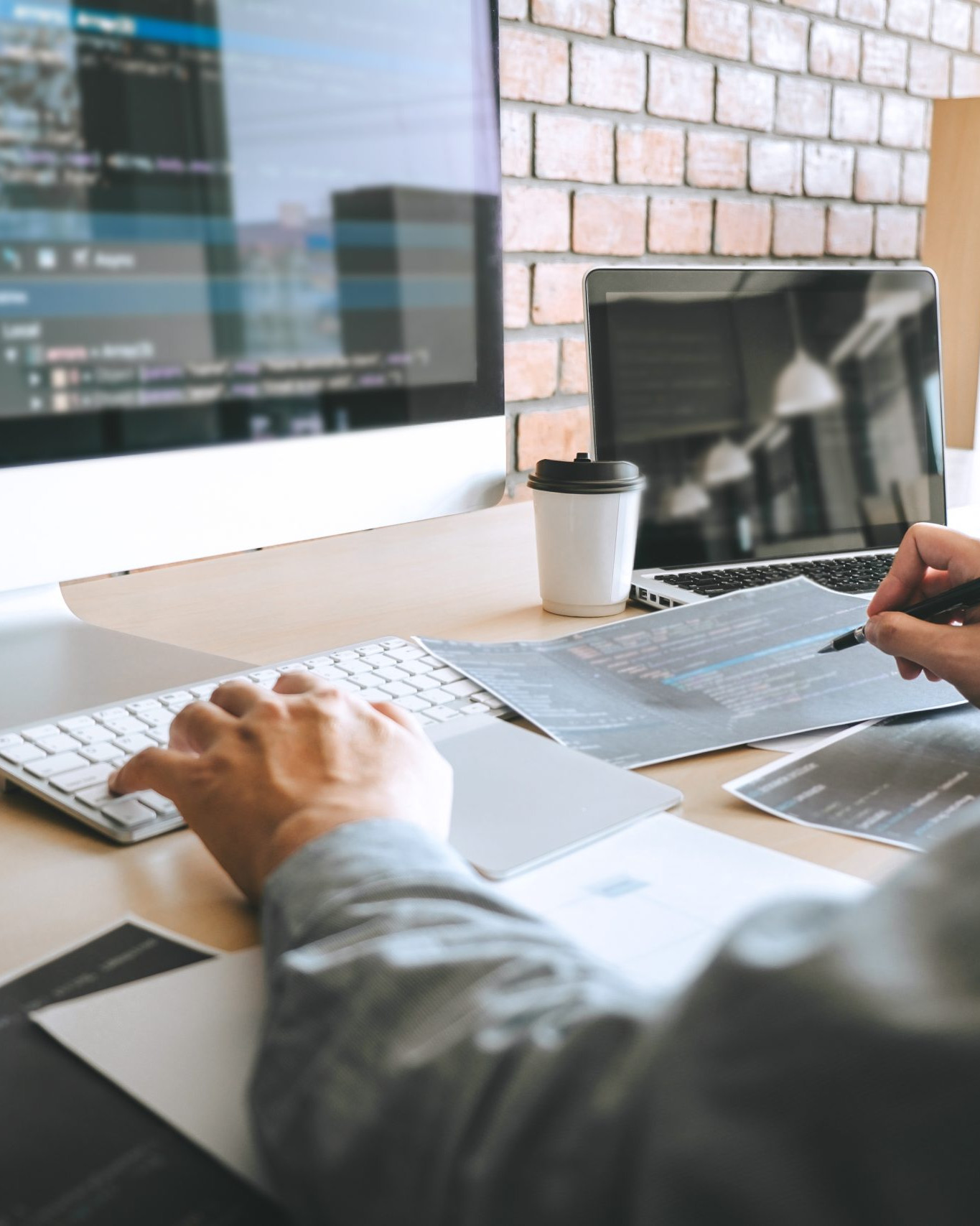 Web developer working on website development and coding at a desktop computer in a modern office.