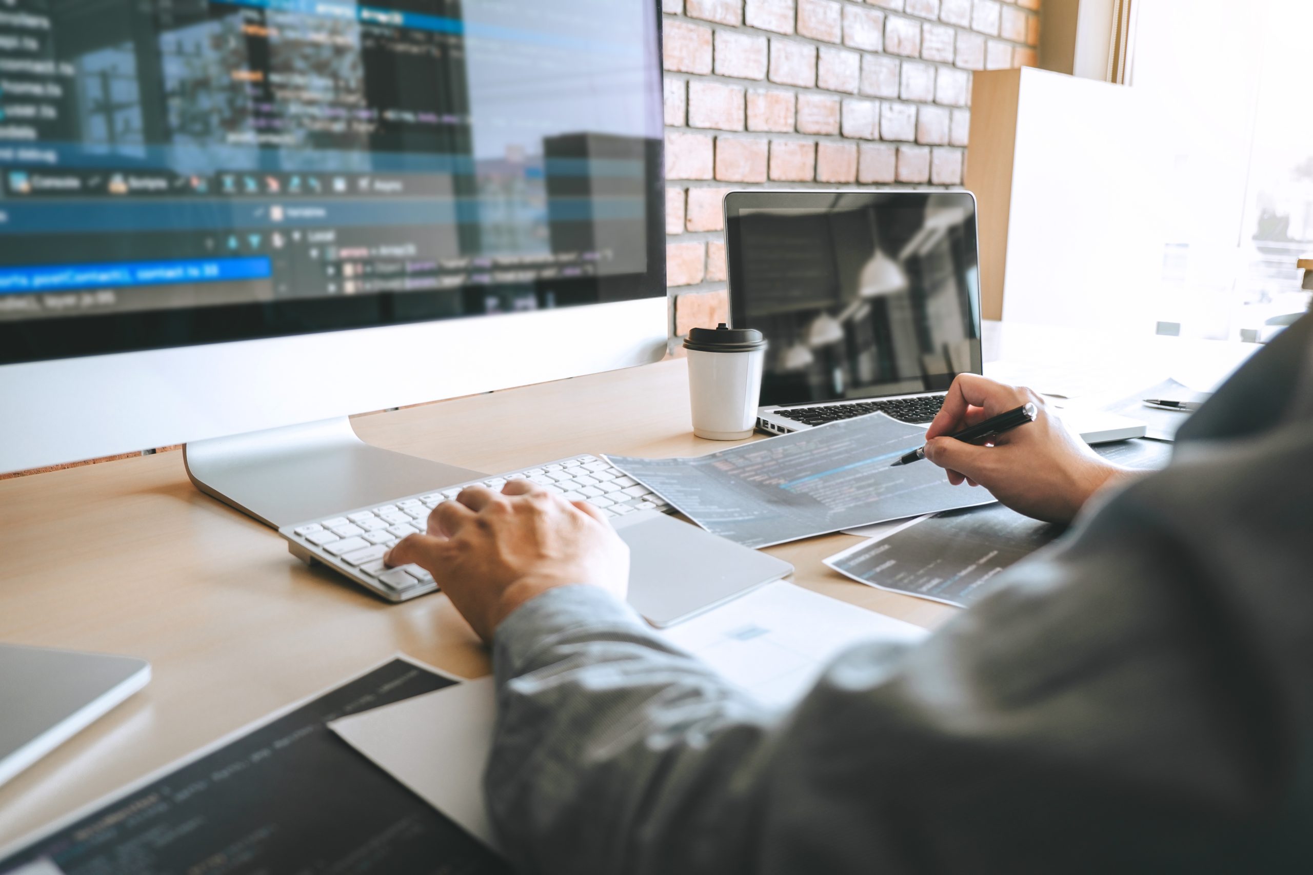 Web developer working on website development and coding at a desktop computer in a modern office.