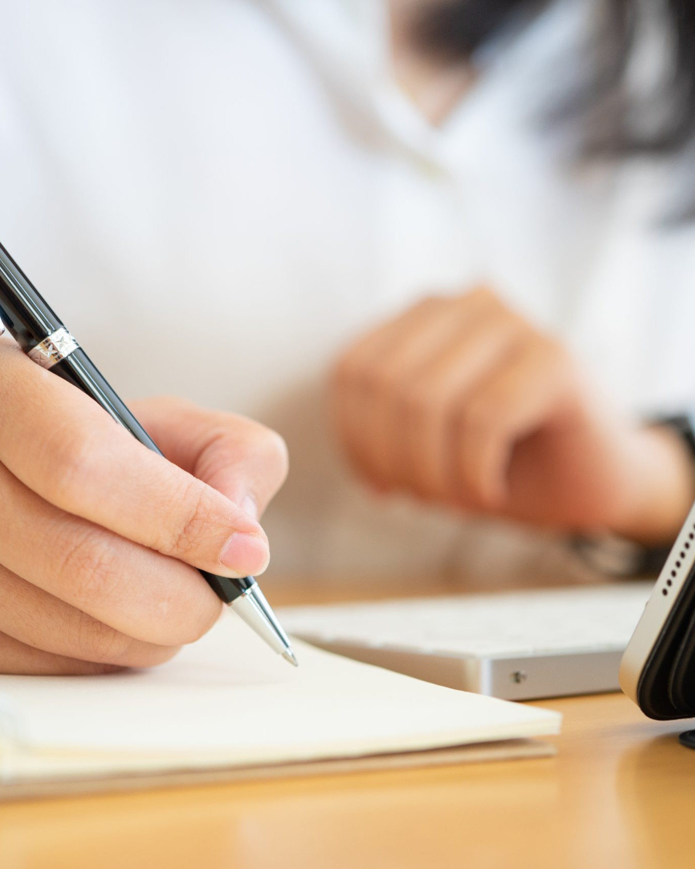 Professional taking notes during a marketing strategy and business planning session using a tablet and notebook.